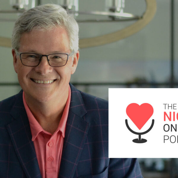 David Cory se penche sur la table de la salle de conférence EITC avec le logo Nice Guys on Business Podcast qui se profile au premier plan.