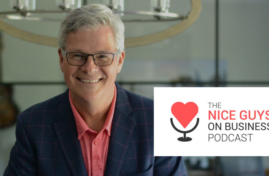 David Cory se penche sur la table de la salle de conférence EITC avec le logo Nice Guys on Business Podcast qui se profile au premier plan.